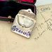 Antique 1911 Crisford & Norris silver stamp case with 'STAMPS' in blue enamel in a black box with red interior.