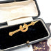 Gold tie clip in an open jewelry box with a white interior
