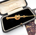 Gold brooch in an open jewelry box on a white background