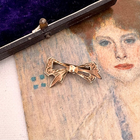 Antique gold lined silver  bow-shaped brooch on an old portrait