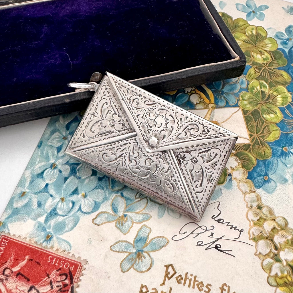 Decorative antique sterling silver stamp case on a floral and vintage-style background