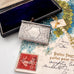Decorative antique sterling silver stamp case on a floral and vintage-style background
