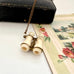 Antique Edwardian stanhope Lourdes binoculars necklace on a chain with a black case and floral illustration in the background.