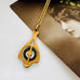 A gold-toned pendant necklace with a vintage compass design, resting on a white surface next to a sepia-toned vintage photograph of a woman.