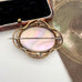 An antique-style brooch featuring an oval iridescent mother-of-pearl center with a gold-toned filigree border and a silver-tone pin bar, displayed next to its dark velvet jewelry box.
