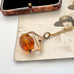 An antique Victorian paste citrine spinning fob necklace, displayed on a vintage-style printed card next to a wooden jewelry box.