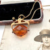 An antique Victorian paste citrine spinning fob necklace, displayed on a vintage-style printed card next to a wooden jewelry box.
