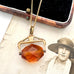 An antique Victorian paste citrine spinning fob necklace, displayed on a vintage-style printed card next to a wooden jewelry box.