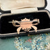 Back of antique Victorian star burst and bow-shaped brooch  displayed on a vintage jewellery box and with a floral card in the background.