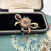 Antique Victorian star burst and bow-shaped brooch  displayed on a vintage jewellery box and with a floral card in the background.