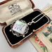 A silver pendant necklace with an iridescent mother-of-pearl square pendant and a white chain, displayed inside an open vintage wooden presentation box with black velvet lining. The inside lid shows the brand name 'R.