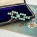 Art Deco era blue paste brooch on a n open jewellery box and with a vintage postcard