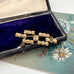 Back of Art Deco era blue paste brooch in an open jewellery box and a vintage postcard