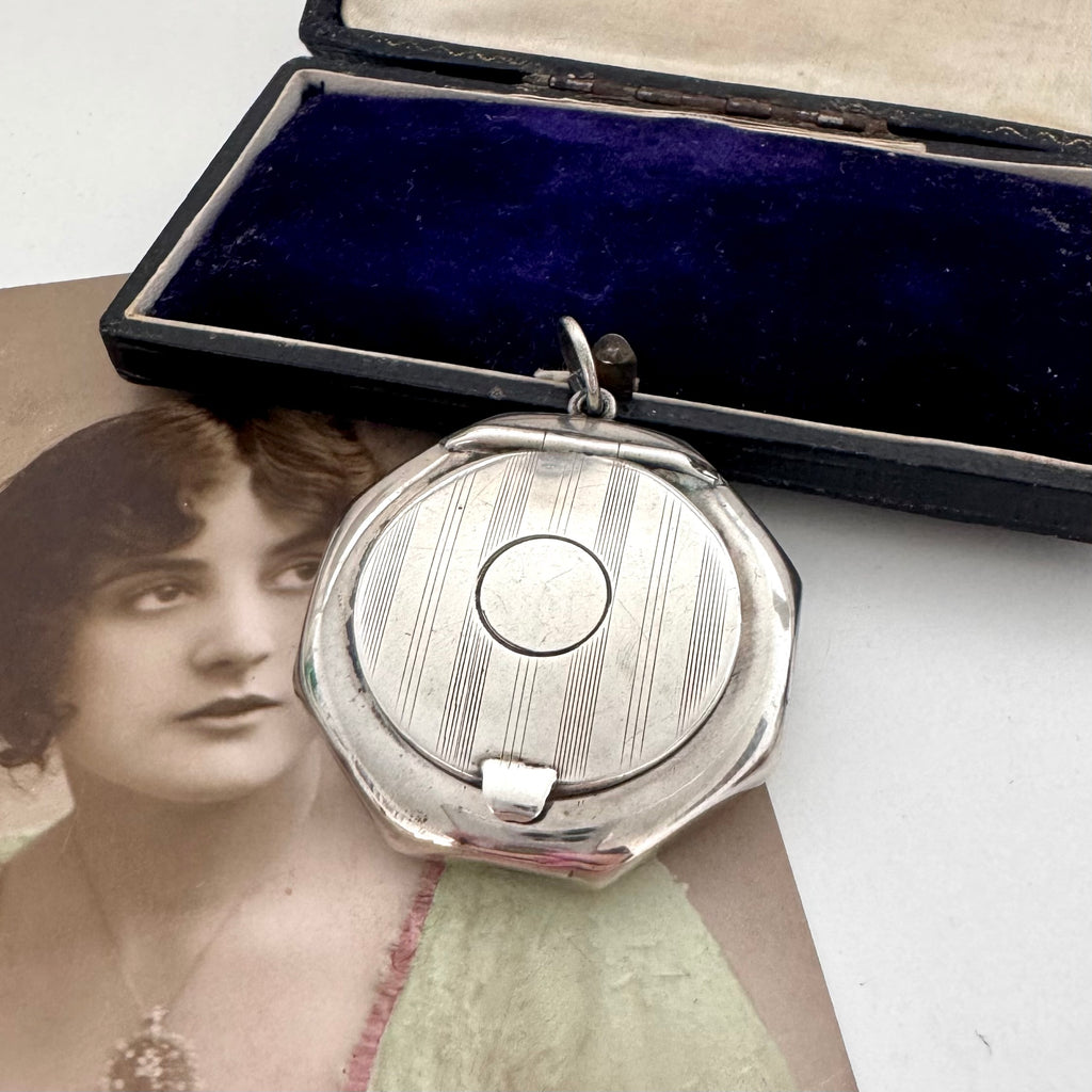 Antique silver compact pendant with an open case on a white background