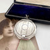 Antique silver compact pendant with an open case on a white background