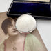 Antique Art Deco silver compact with an open box and an old photograph of a woman on a white surface.