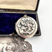 Sterling silver art nouveau repousse floral locket on a white background with an engraved cherub design in the background and on a box