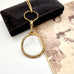 Antique gold magnifying glass necklace on a white surface with an old photograph