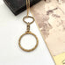 Antique gold fill magnifying glass necklace on a white surface with an old photograph.