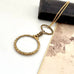 Antique magnifying glass necklace on a white background