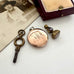 Vintage key and locket with initials on a white surface next to an old photograph.