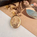 Gold locket on a textured surface with an old photograph in the background