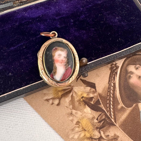 Antique rolled gold locket with hand painted portrait on an open jewellery box