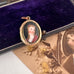 Antique rolled gold locket with hand painted portrait on an open jewellery box