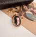 Antique rolled gold locket with hand painted portrait on an open jewellery box
