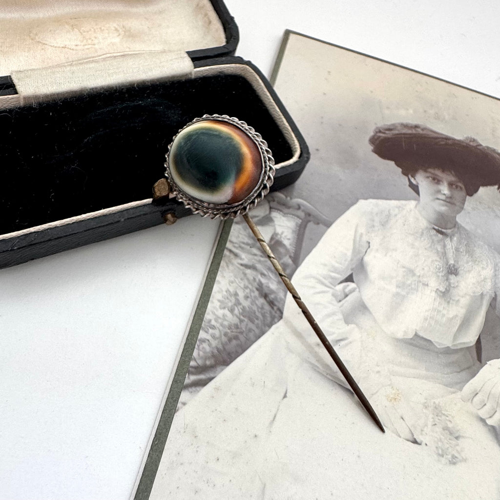 Antique operculum shell pin on an old photograph of a woman in a white dress and hat.