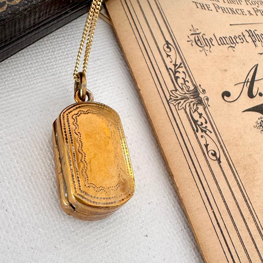 Antique pinchbeck vinaigrette on a chain with an old document in the background