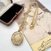 An antique oval locket pendant necklace with an ornate floral engraving, resting on a vintage sepia-toned photograph of a woman. The locket is attached to a gold-tone chain with a lobster clasp.
