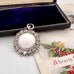 Antique silver watch fob in an open jewelry box with a Christmas-themed card underneath