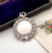 Antique silver watch fob in an open jewelry box with a Christmas-themed card underneath