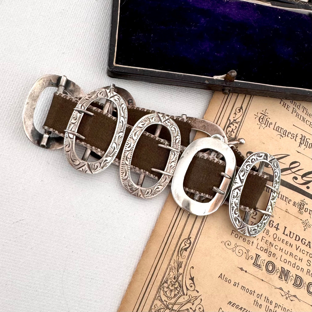 Bracelet made from antique silver buckles on an old advertisement paper with a black vintage jewellery box.