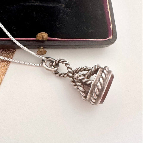Antique silver and carnelian watch fob on a white background and with an old jewellery box