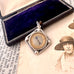 Antique silver compass watch fob with a displayed on an old photograph and text.