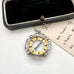 Antique sterling silver watch fob on an old jewellery box and with an old postcard.