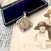 Antique silver compass watch fob with a displayed on an old photograph and text.
