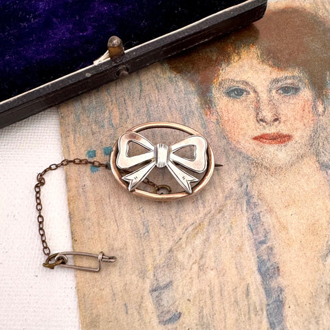 Antique silver bow brooch on an old photograph with a purple velvet box