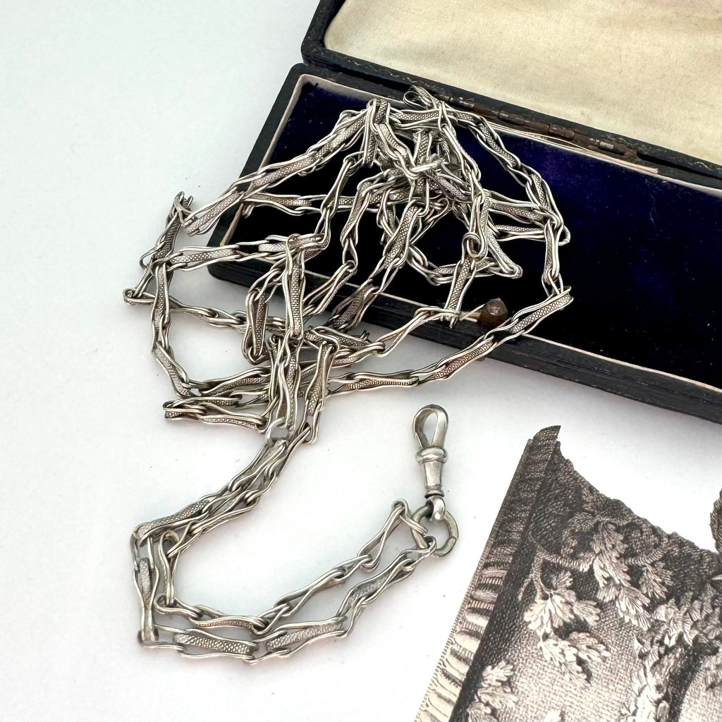 Antique silver fancy link guard chain on an old jewellery box and with an engraved picture in the corner