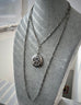 Antique silver fancy link guard chain and silver repousse locket on a grey mannequin