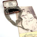 A vintage silver plated guard chain necklace draped over an open brown presentation box, placed on top of an antique black-and-white portrait photograph. 