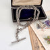 Antique silver watch chain necklace with a clasp on an open jewelry box with vintage cards underneath.