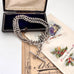 Antique silver watch chain necklace with a clasp on an open jewelry box with vintage cards underneath.