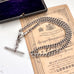 Antique silver watch chain necklace on an antique advertising card and a vintage jewellery box