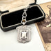 Antique sterling silver watch fob and love knot chain on a white surface next to vintage photograph