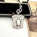 Antique sterling silver watch fob and love knot chain on a white surface next to vintage photograph