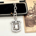 Antique sterling silver watch fob and love knot chain on a white surface next to vintage photograph