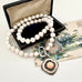 Pearl and antique 1928 watch fob necklace with a silver clasp on an open jewelry box with floral card in the background